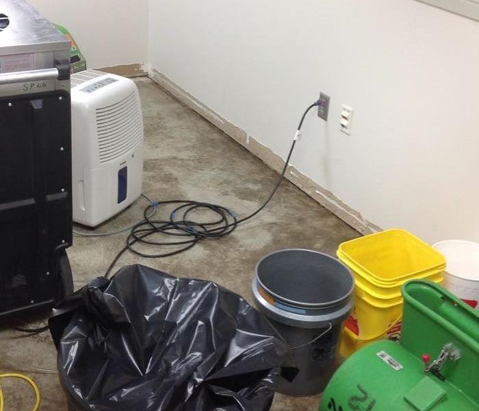 A large dehumidifier and fan are lined up on the floor, ready to dry up the unwanted water.