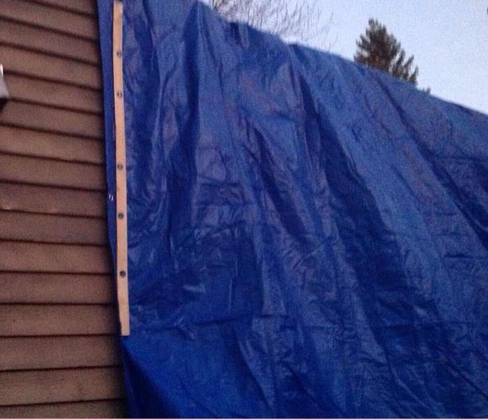 A blue tarp covers the external fire damage of siding on home 